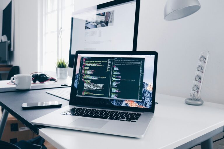 Laptop showing code on a busy workspace, representing digital tools in development